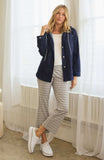 Casual outfit, women's fashion, navy jacket, white top, patterned pants, white sneakers, indoor setting, stylish look.
