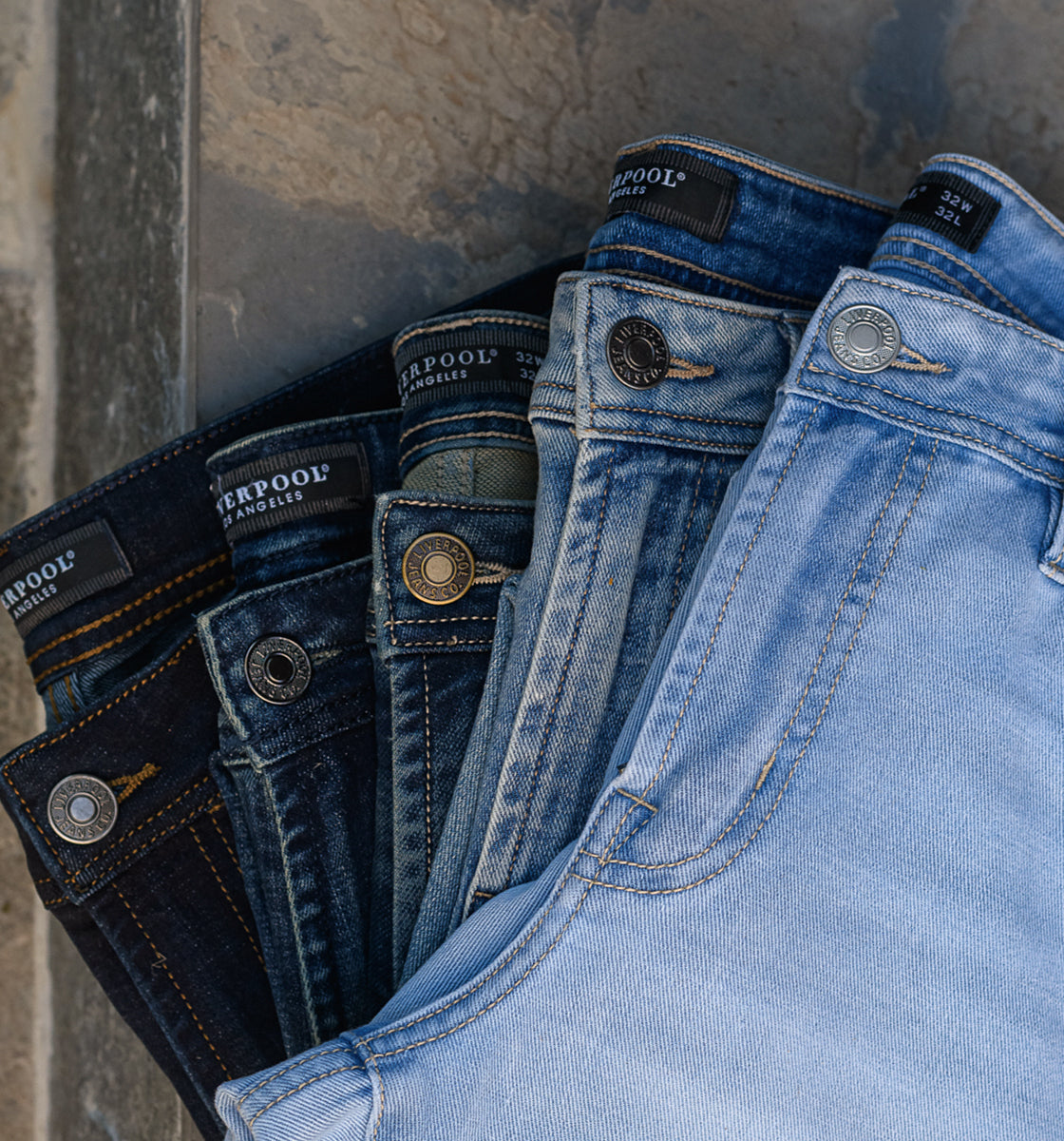 Variety of blue jeans in different shades stacked together.