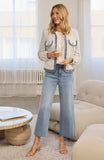 woman holding glass of wine wearing stylish jacket and denim jeans in modern interior